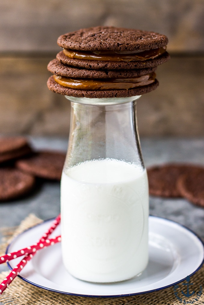 Mexican Chocolate Sandwich Cookies with Dulce de Leche Filling on top of a milk bottle
