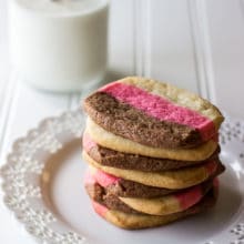 Stack of Neapolitan Butter Cookies on white plate with lace edge with bottle of milk in background.