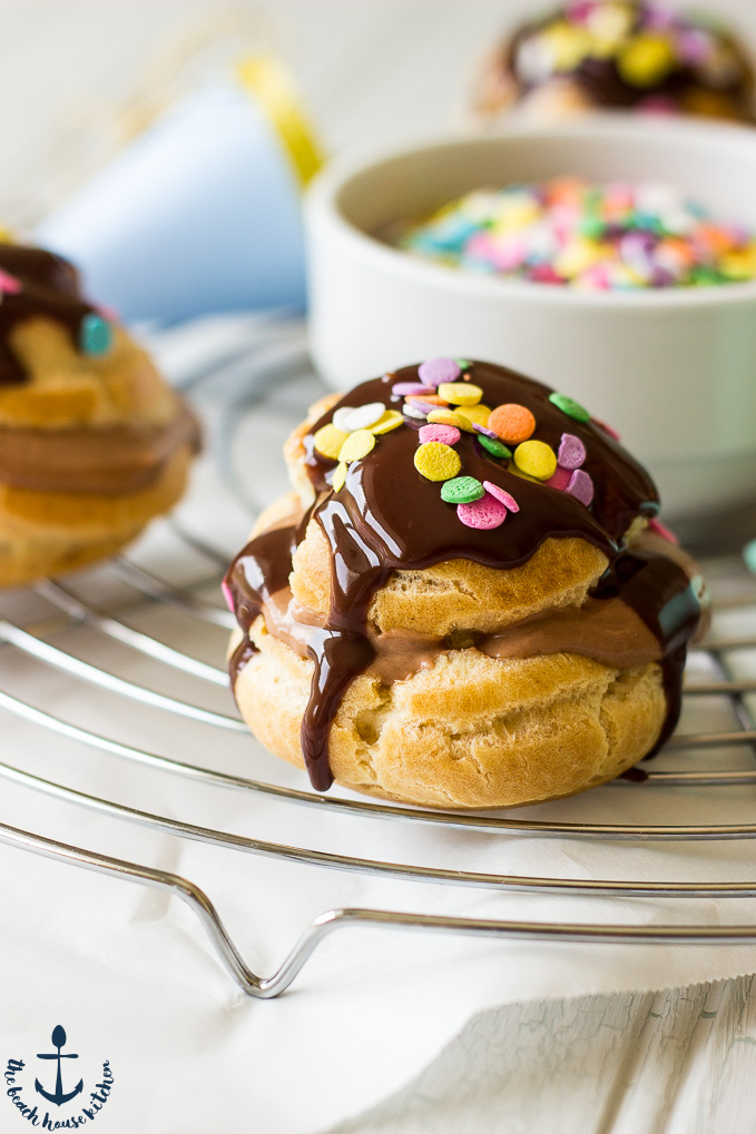 Close up of Nutella Cream Puffs drizzled with chocolate and topped with colored sprinkles