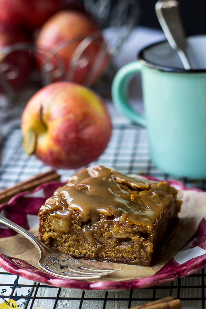 Caramel Glazed Apple Butter Blondie on a red and white check plate with an apple and green mug in background.