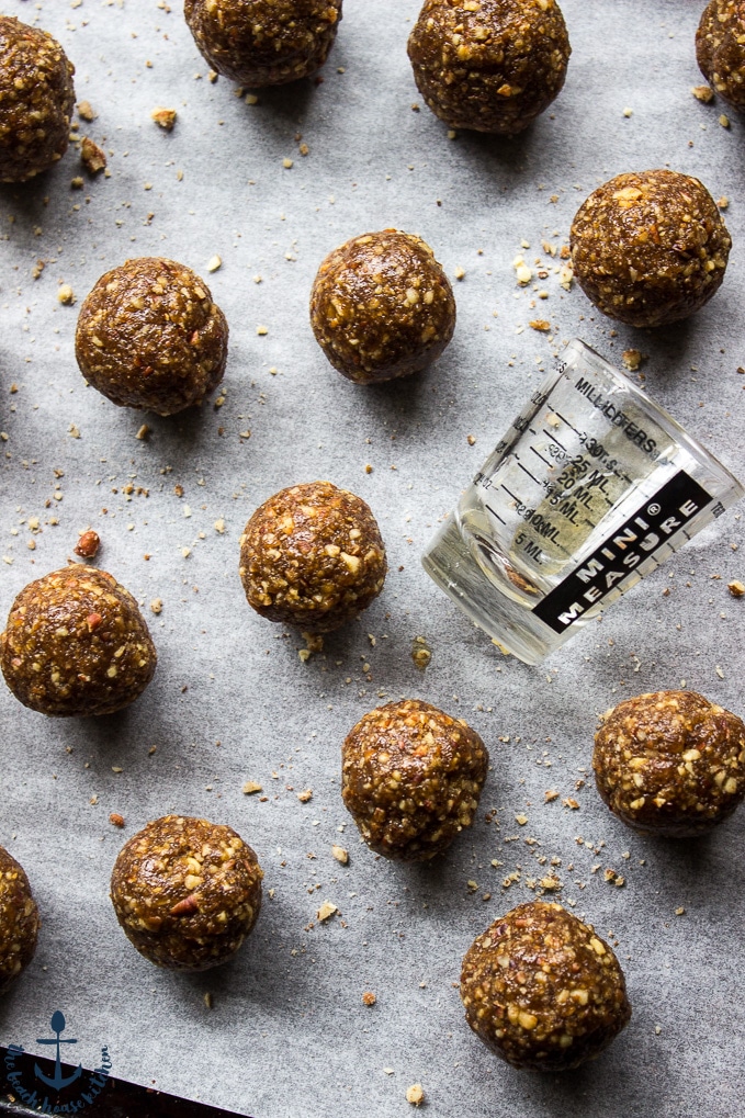 Pecan Pie Truffles without chocolate coating on baking sheet lined with parchment paper and a glass shot glass.