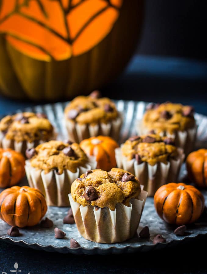 Pumpkin Chocolate Chip Muffins on a silver tray with carved pumpkin in background.