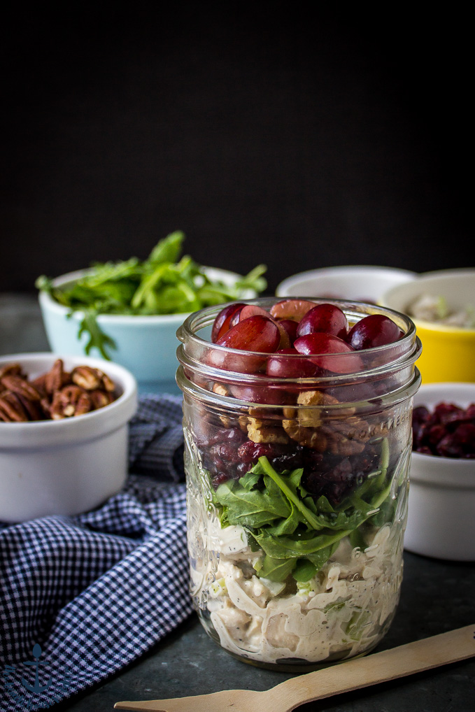Turkey Salad with Grapes, Pecans and Cranberries in a Jar with pecans and arugula in white bowls and blue and white check napkin.