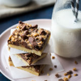 A stack of three easy toffee chocolate chip bars on a pink plate with a bottle of milk with two straws.