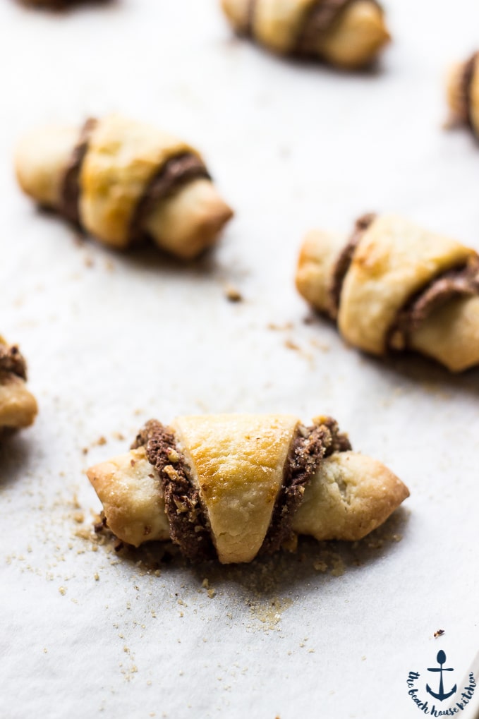 Rolled Nutella Pecan Rugelach on parchment lined baking sheet after baking.