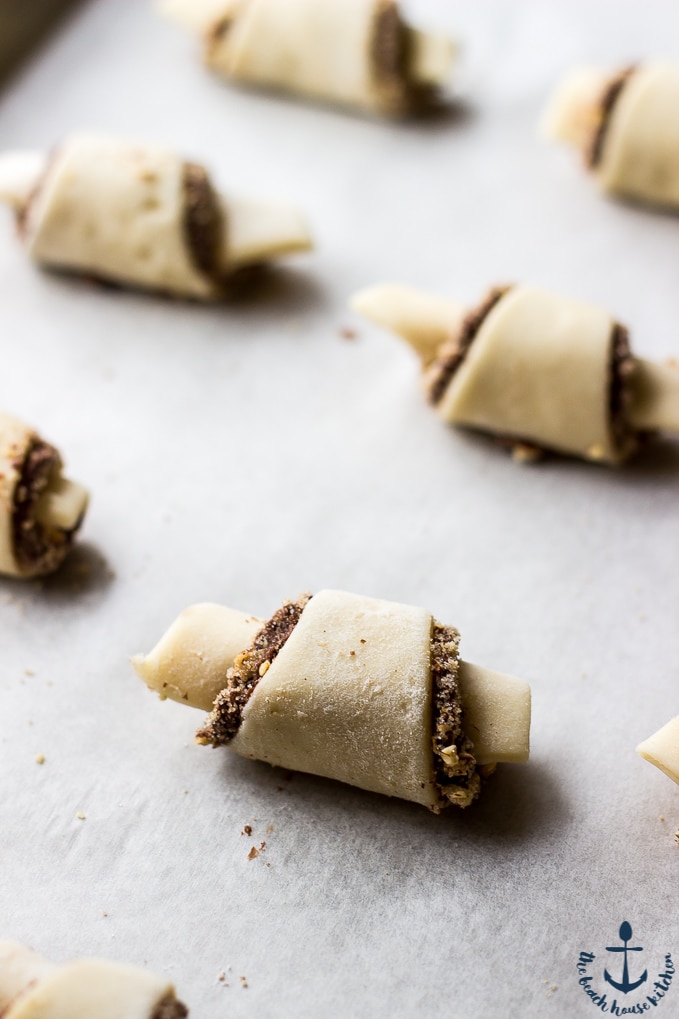 Rolled Nutella Pecan Rugelach on parchment lined baking sheet before baking.