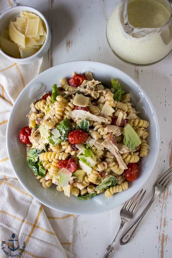 Chicken, Bacon, Avocado Caesar Pasta Salad in a white bowl on a white background.