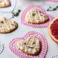 Pink Grapefruit and Thyme Shortbread Hearts on heart doilies with thyme leaves and pink grapefruit in background.