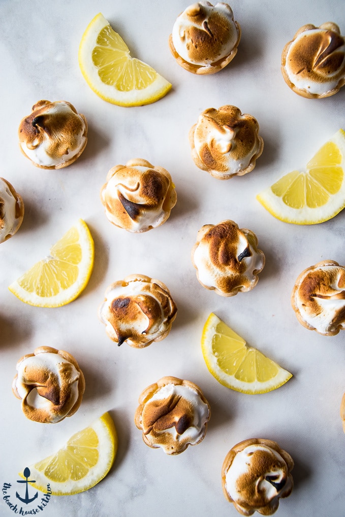 Overhead photo of Mini Lemon Meringue Pies and lemon slices on a white background