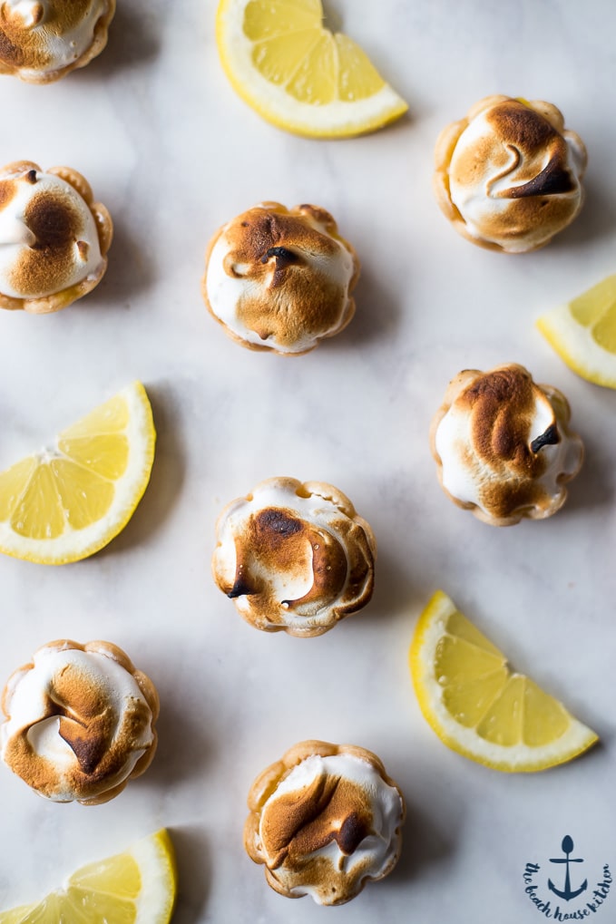 Overhead photo of Mini Lemon Meringue Pies and lemon slices on a white background