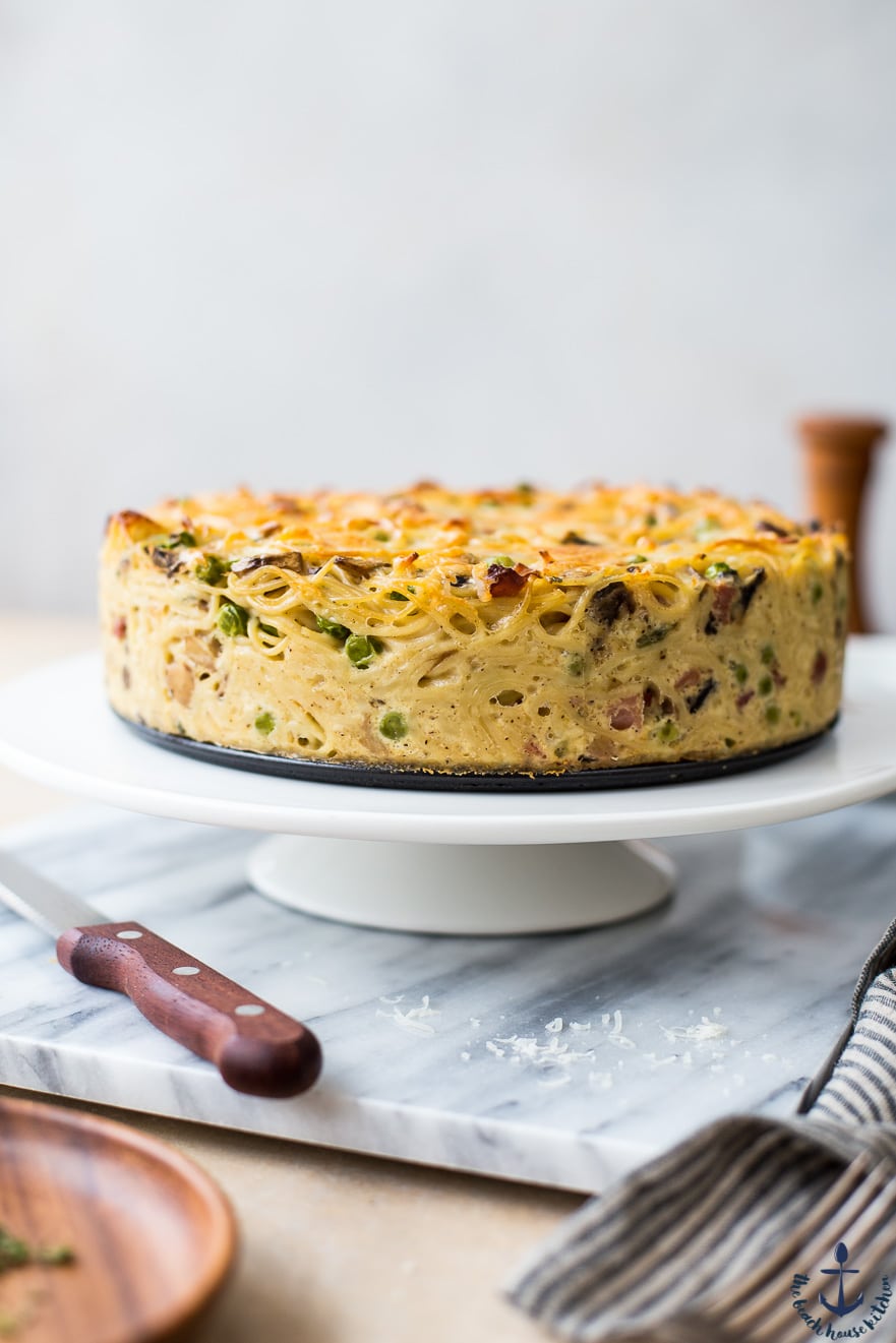 A Spaghetti Pie with Mushrooms, Peas and Pancetta on a white stand