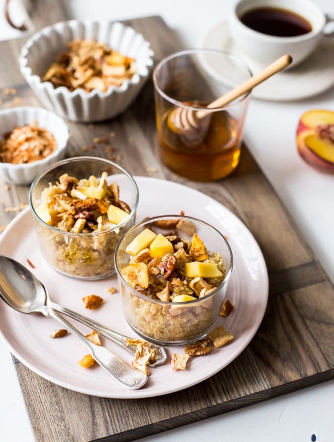 Two Peachy Quinoa breakfast bowls in glass cups on pink plate