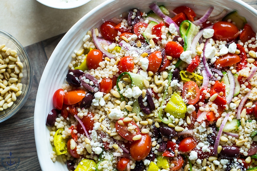 Overhead photo os Greek Couscous Salad in a white bowl