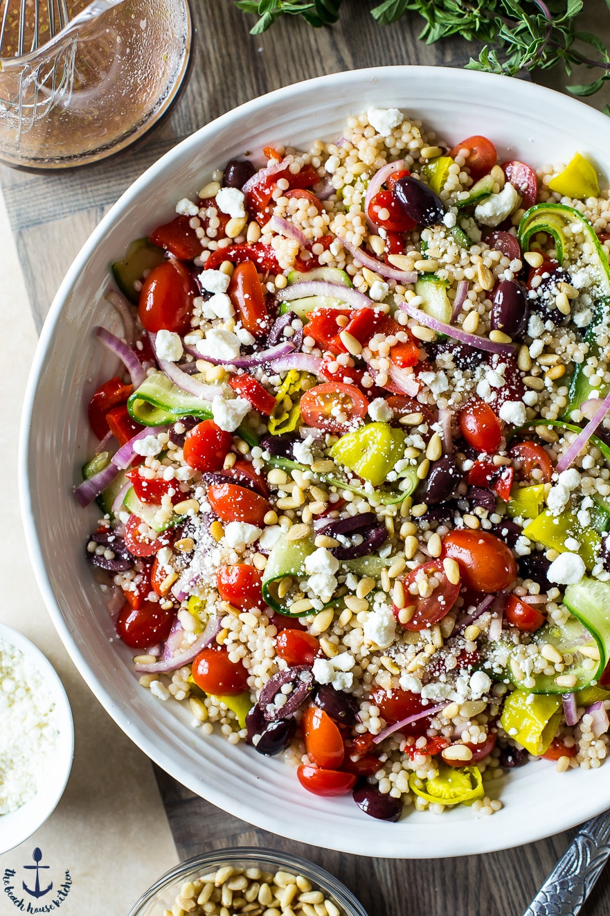Overhead photo os Greek Couscous Salad in a white bowl.