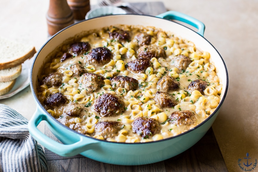 Swedish Meatball Pasta Bake in a blue pot with three piece of bread blurred in the background