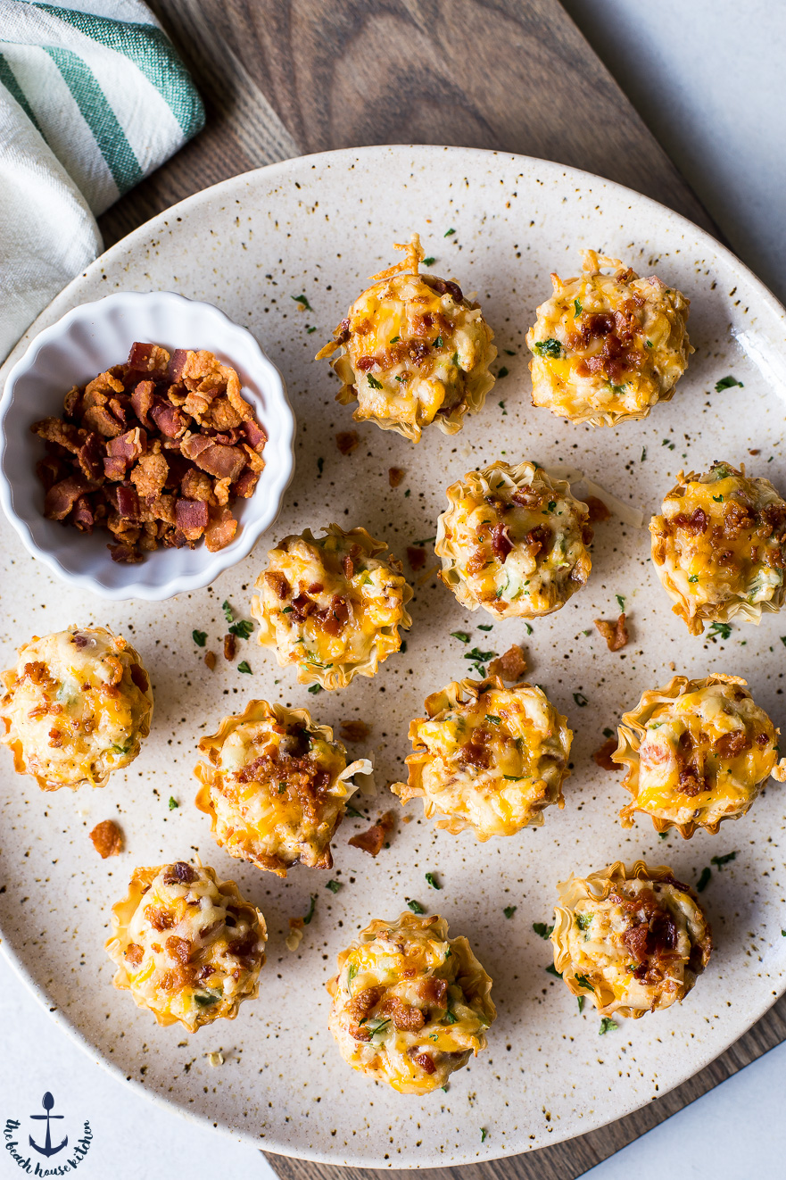Overhead photo of Jalapeno Popper Pastry Bites on a plate with a small bowl of bacon bits.