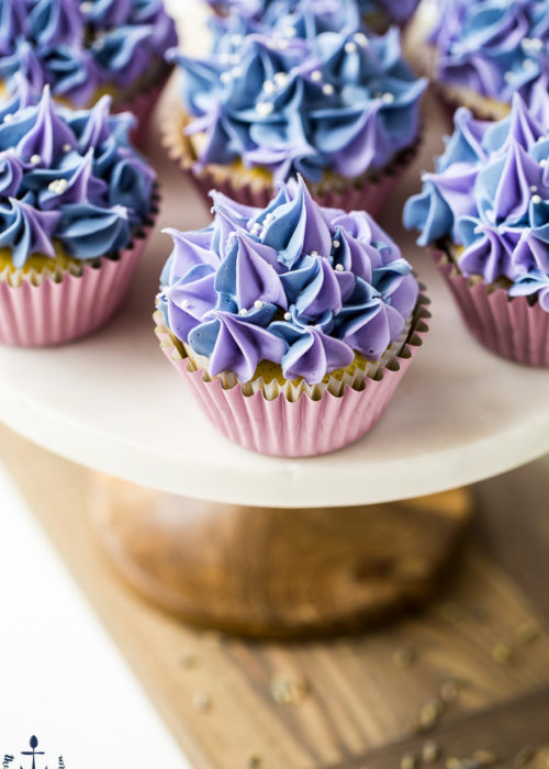 Photo of lemon olive oil cupcakes with lavender buttercream on a cake plate with wooden stand