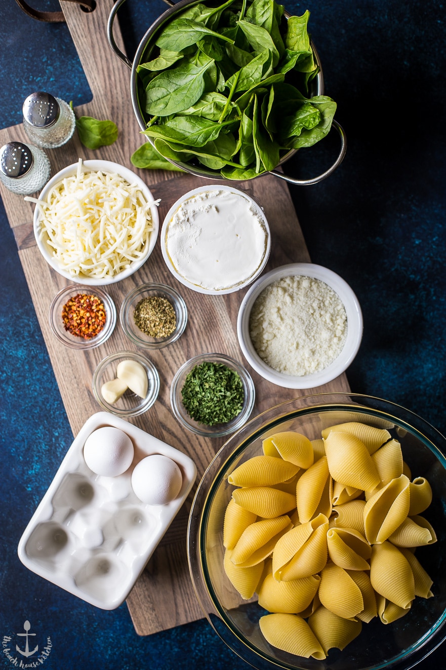 Overhead photo of ingredients for easy spinach stuffed shells in bowls on wooden board