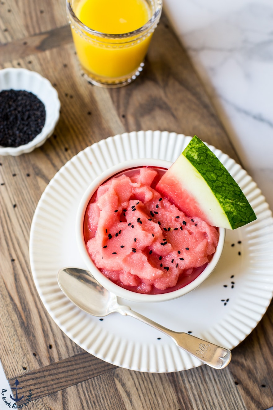 Overhead photo of watermelon creamsicle smoothie bowl on a white plate on a wooden board