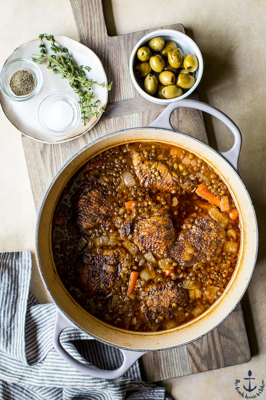 Overhead photo of za'atar chicken thighs with green lentils in a Dutch oven