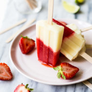 Miami Vice Boozy Popsicles on a pink plate surrounded by a few halved strawberries