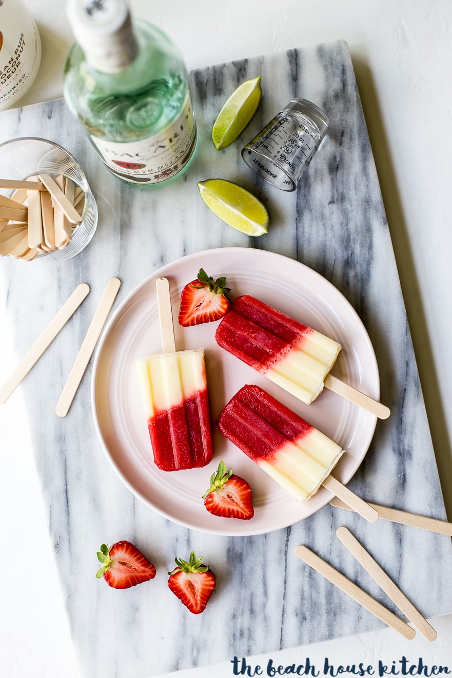 Overhead photo of Miami Vice boozy popsicles on pink plate with sliced strawberries
