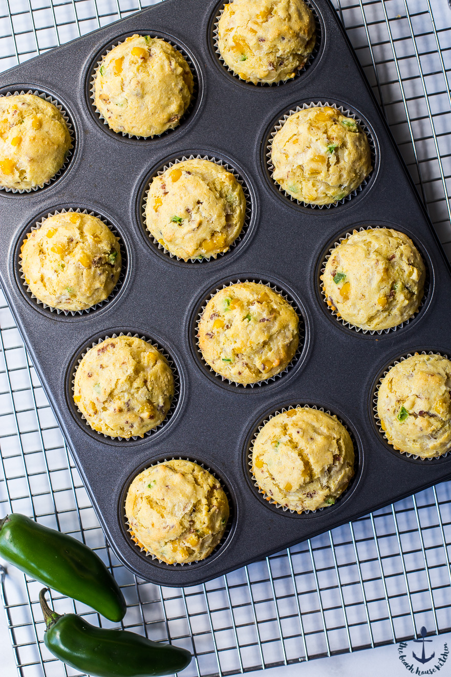Overhead photo of cheddar bacon jalapeno corn muffins in muffin pan on wire rack