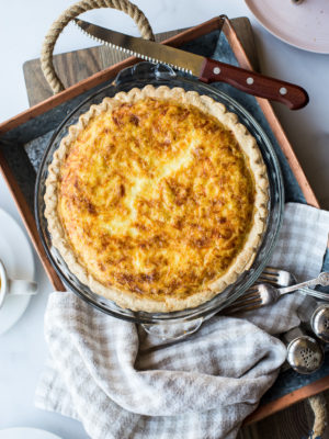 Overhead photo of quiche lorraine in a pie plate on a silver tray