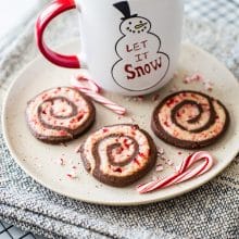 Chocolate peppermint pinwheel cookies on a plate with a mug of hot cocoa
