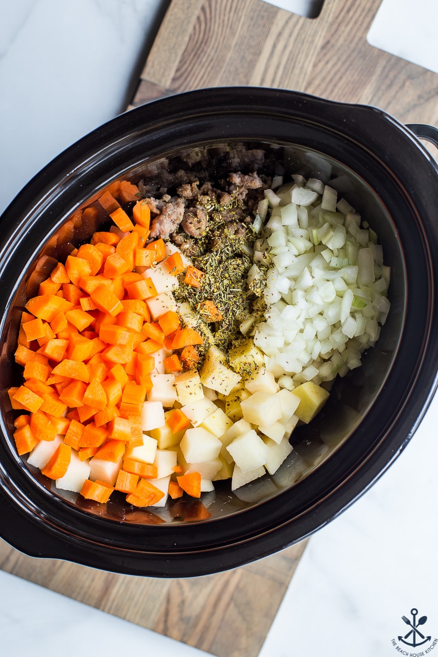 Overhead photo of slow cooker filled with carrots, potatoes, onions and bratwurst
