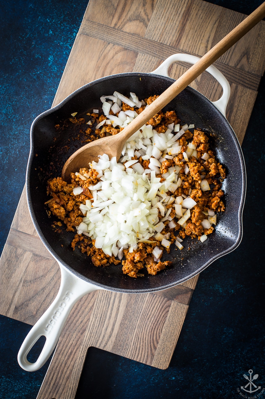 Skillet filled with ground chorizo sausage and chopped onion
