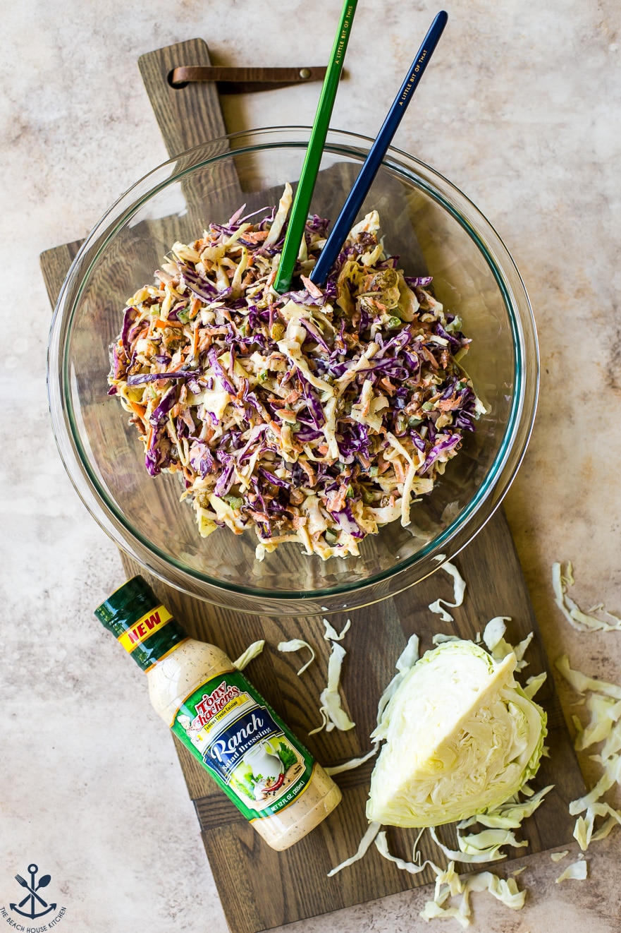 Overhead photo of bacon ranch cole slaw in a glass bowl on a wooden board