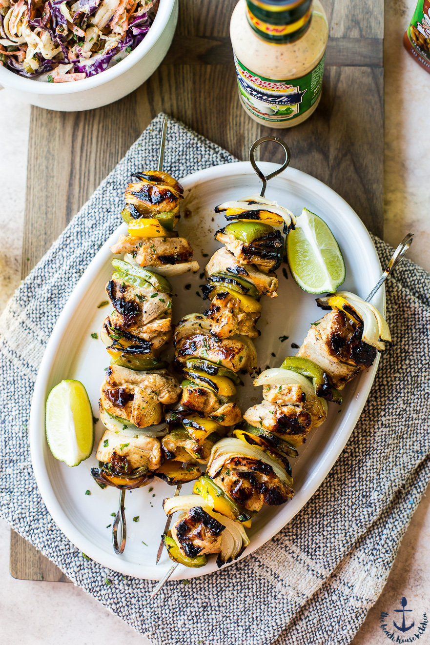 Overhead photo of chicken skewers on a white oval plate on a wooden board