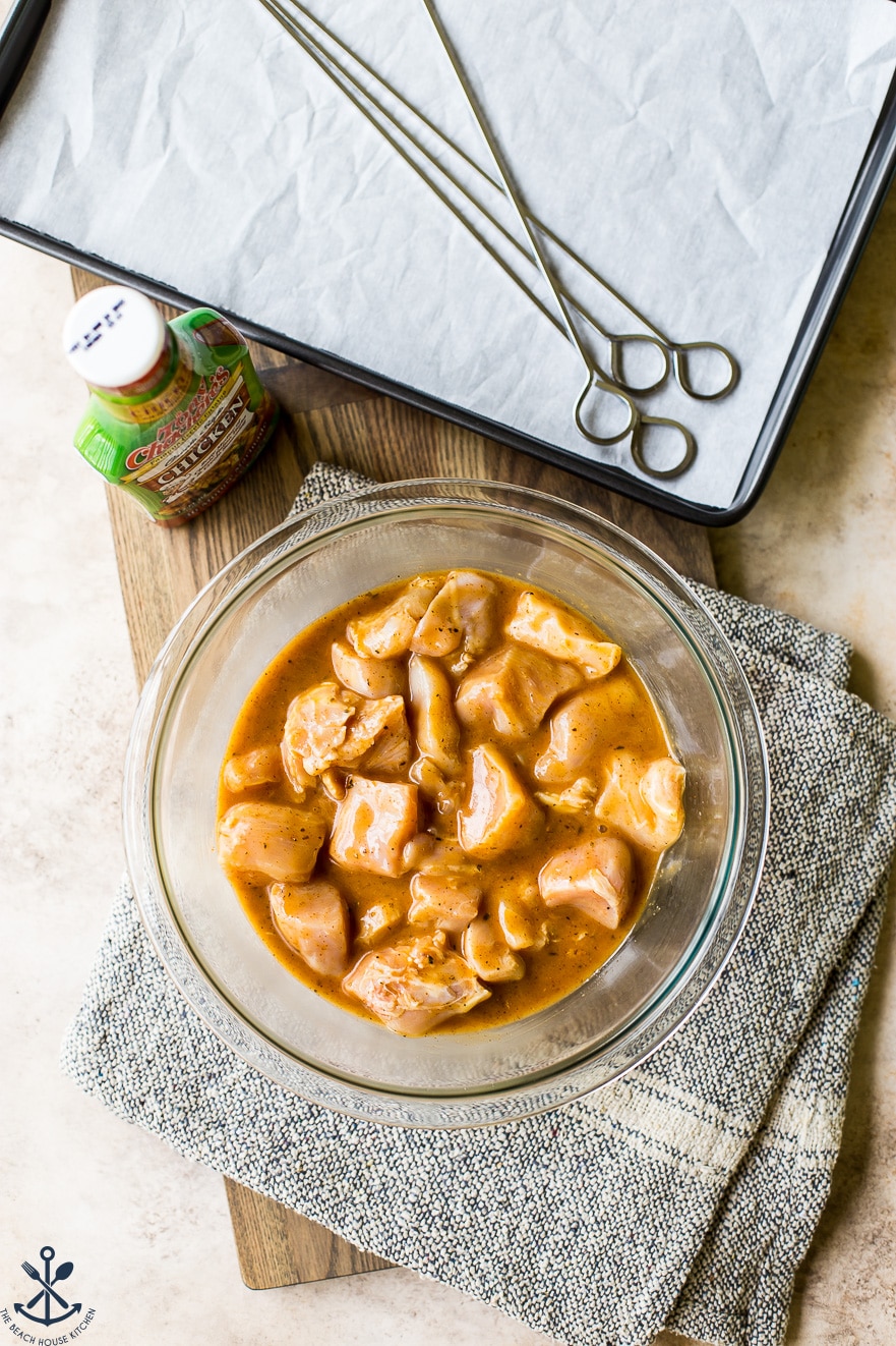 Overhead photo of precooked chicken pieces marinating in a glass bowl
