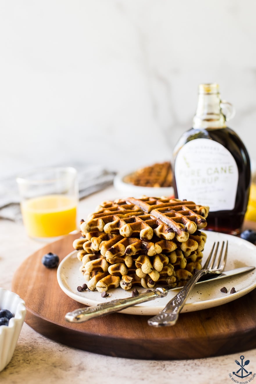 Photo of chocolate chip banana bread waffles on a plate on a wooden serving board