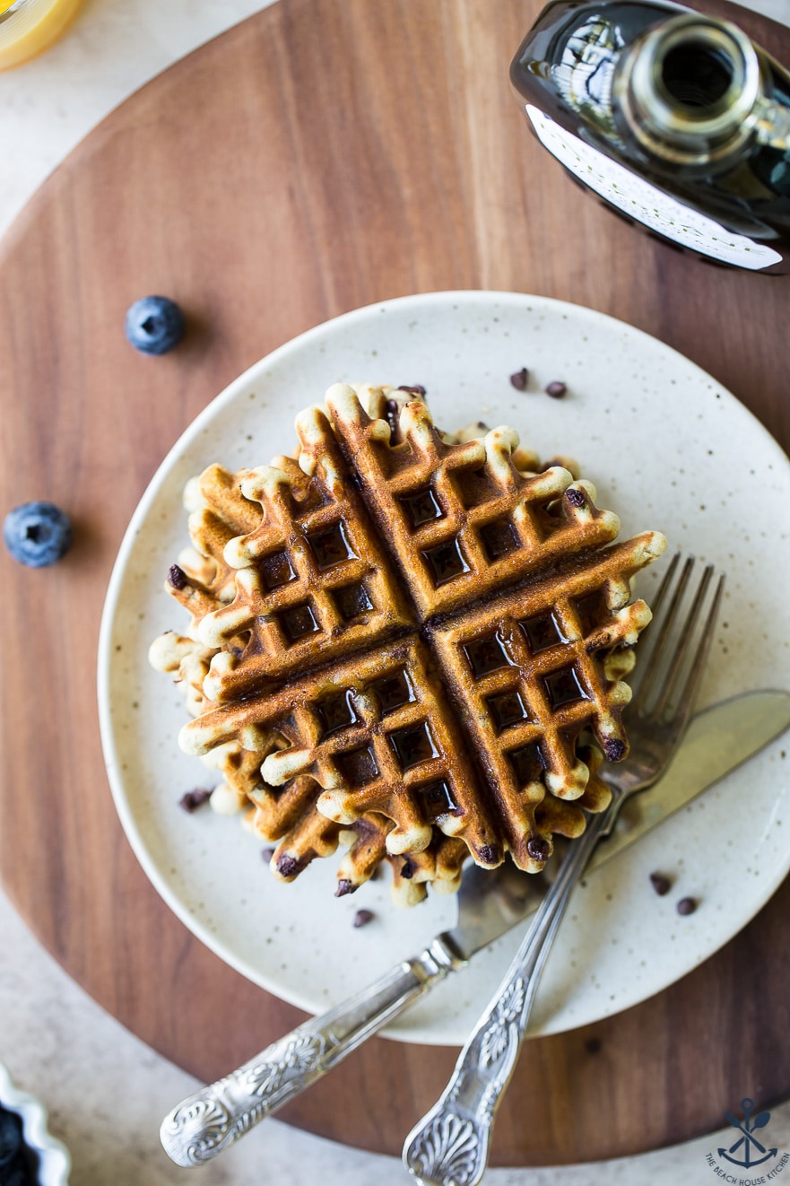 Overhead photo of chocolate chip banana bread waffles on a plate on a wooden board