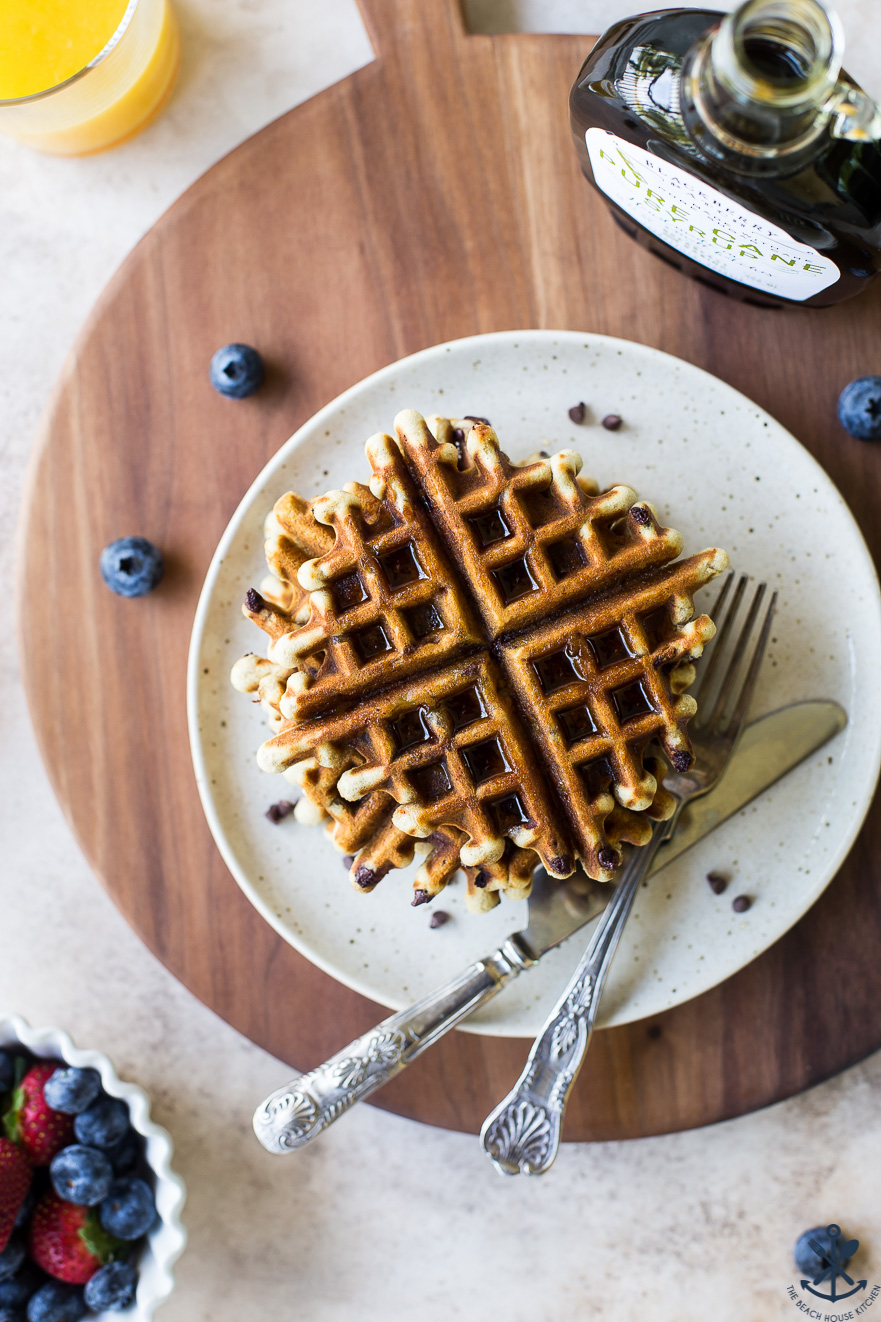 Overhead photo of chocolate chip banana bread waffles on a plate on a wooden board