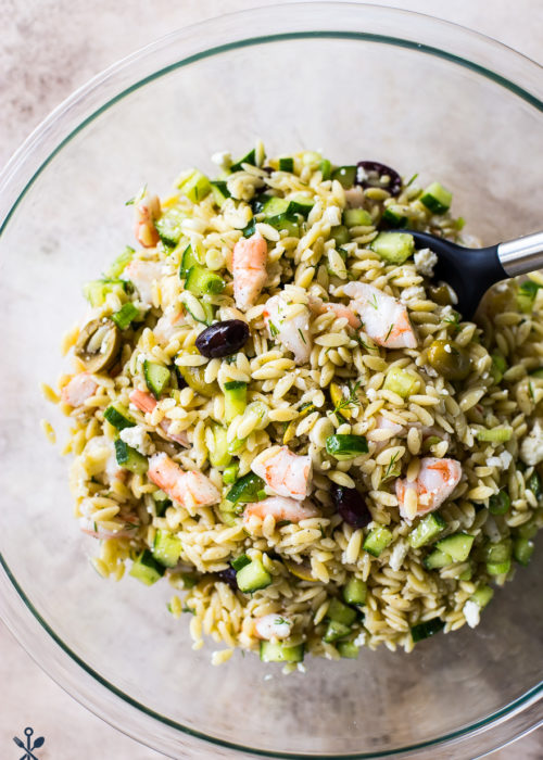 Overhead photo of glass bowl filled with lemony orzo pasta salad with shrimp