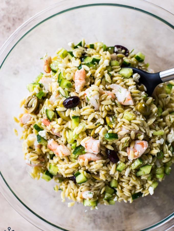 Overhead photo of glass bowl filled with lemony orzo pasta salad with shrimp
