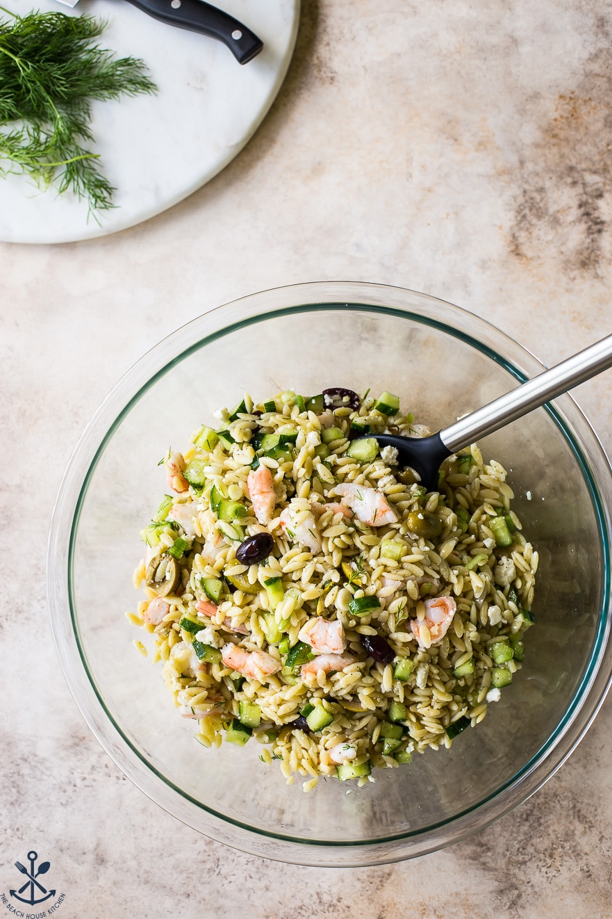Overhead photo of lemony orzo pasta salad with shrimp in glass bowl