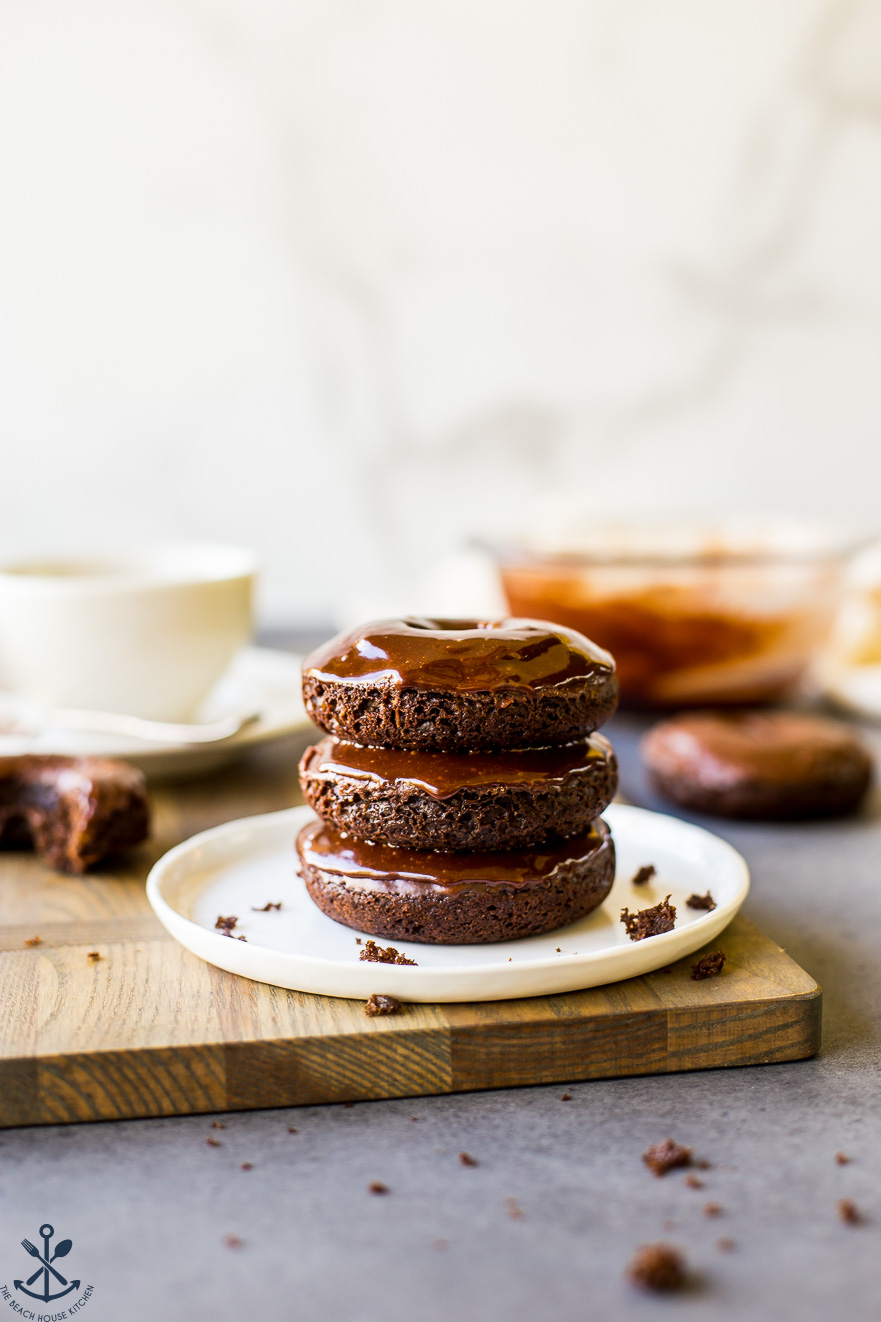 Stack of three cocoa coffee baked donuts on a white plate
