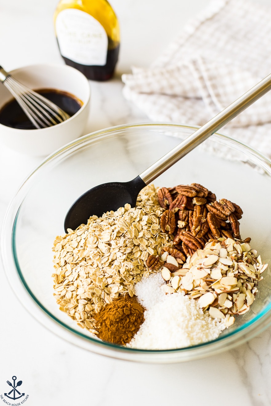 Ingredients for maple cinnamon granola in a glass bowl with a spoon
