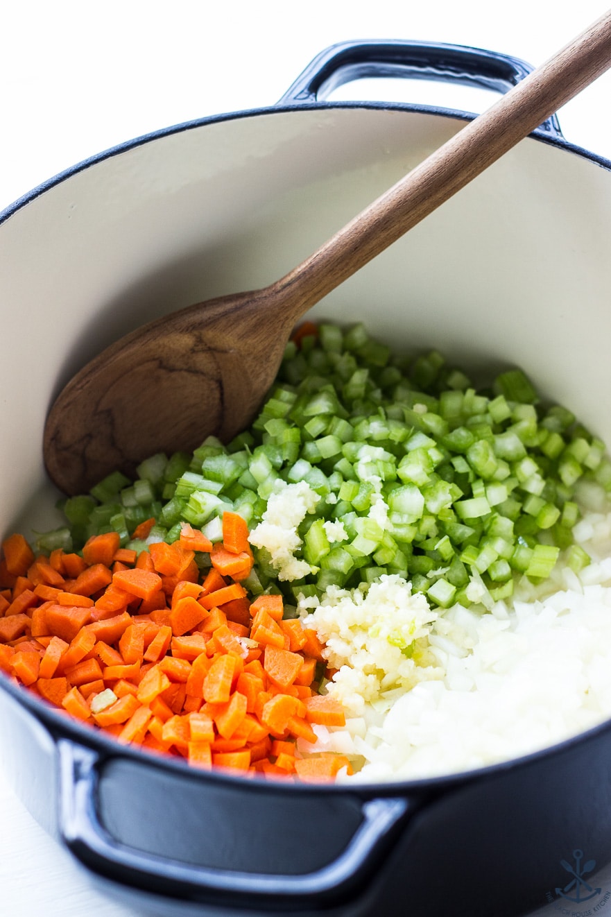 Up close photo of large pot filled with chopped carrots, celery, onions and garlic