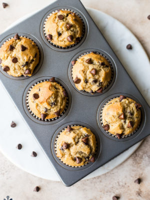 Overhead photo of Easy Chocolate Chip Muffins in muffin tin on a round white marble board