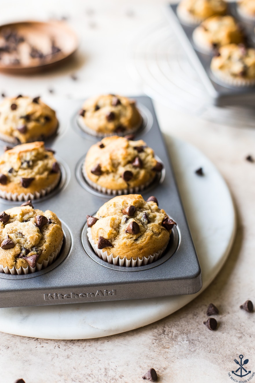 Easy Chocolate Chip Muffins in a muffin tin on a round white marble board