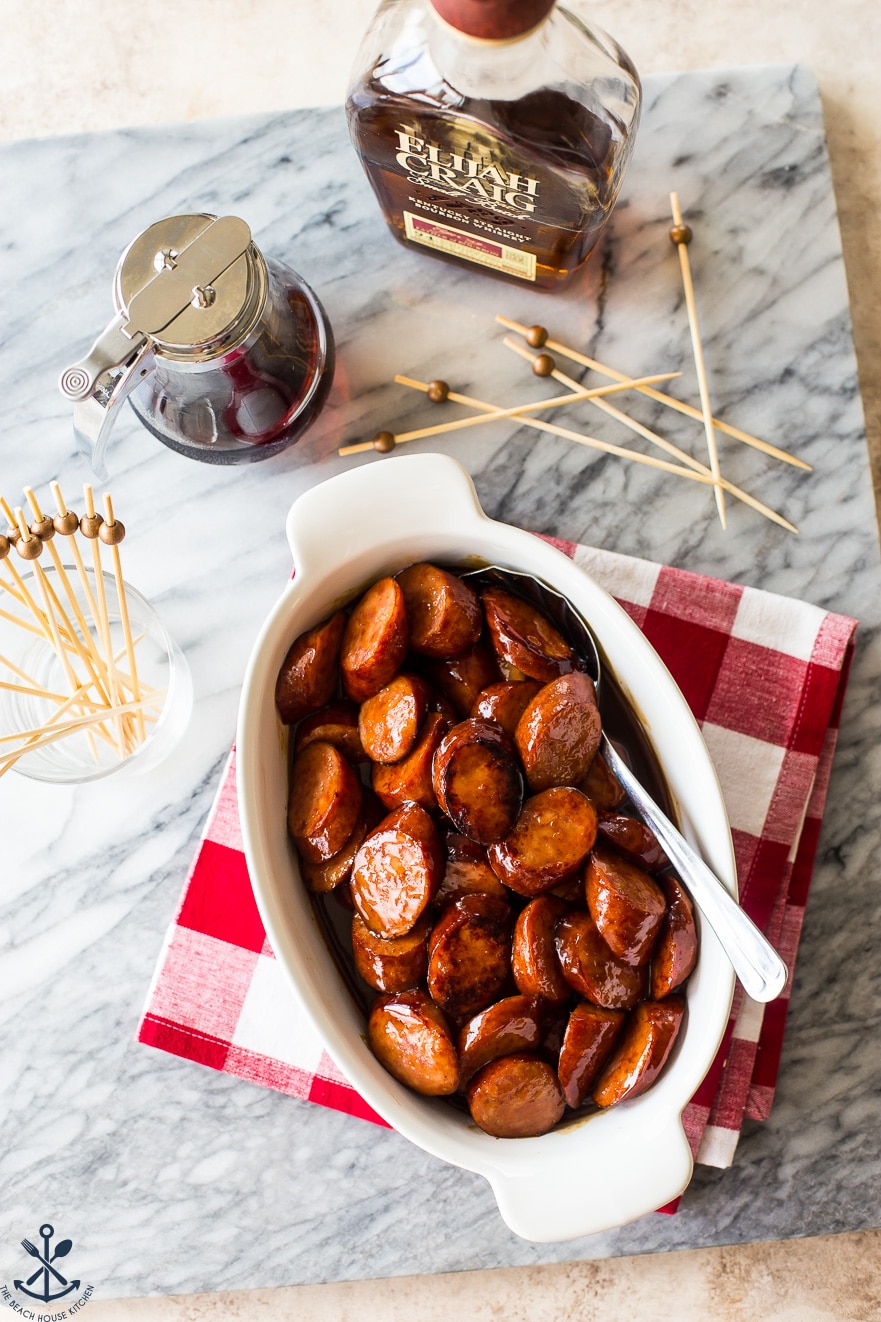 Overhead photo of white oval baking dish filled with maple bourbon BBQ kielbasa bites
