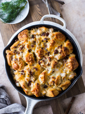 Overhead photo of cheesy shrimp skillet monkey bread in a white skiller on a wood board