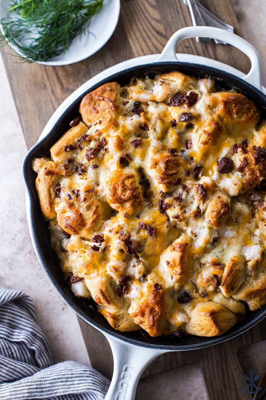 Cheesy Shrimp Skillet Monkey Bread in a white skillet on a wooden board