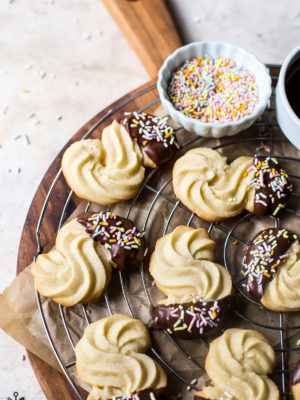 Chocolate Dipped Danish Butter Cookies on a round wire rack on a wooden board