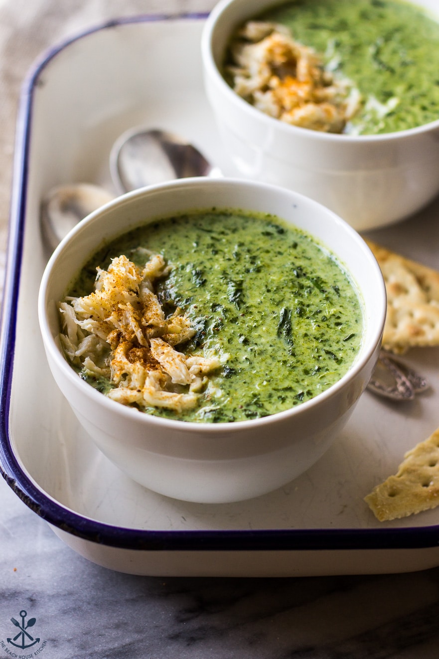 Creamy Spinach Soup with Crabmeat in white bowls in an enamel tray with spoons and crackers